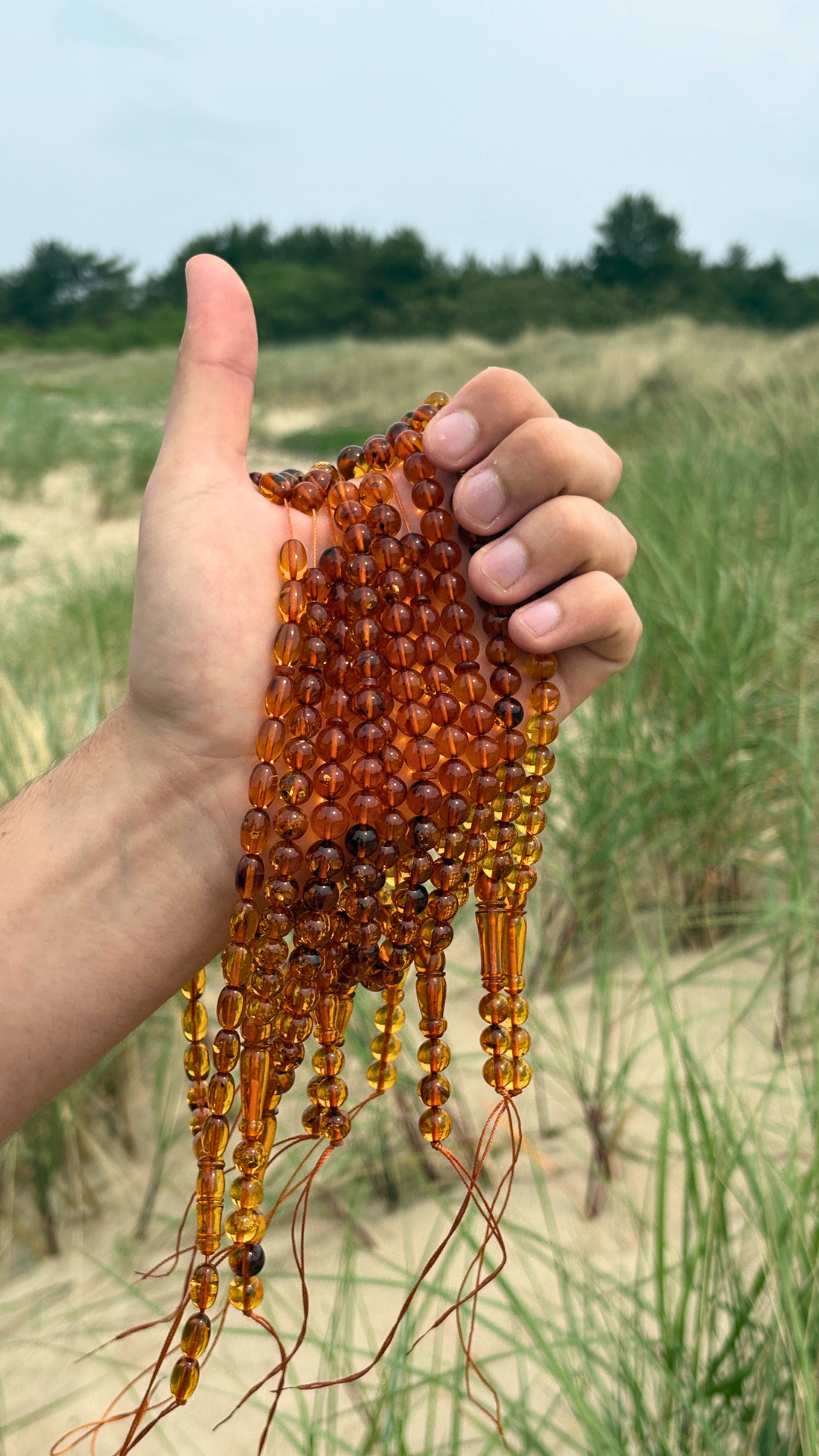 Baltic amber tasbih held in hand on the Lithuanian shore